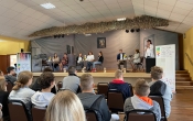 Widok siedzacych uczniowi patrzacych  na scene z czytajacymi lektorami