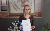 Laureatka konkursu w tle koncik patrona szkoly.