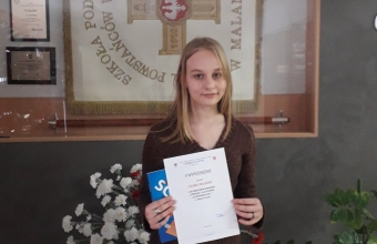 Laureatka konkursu w tle koncik patrona szkoly.
